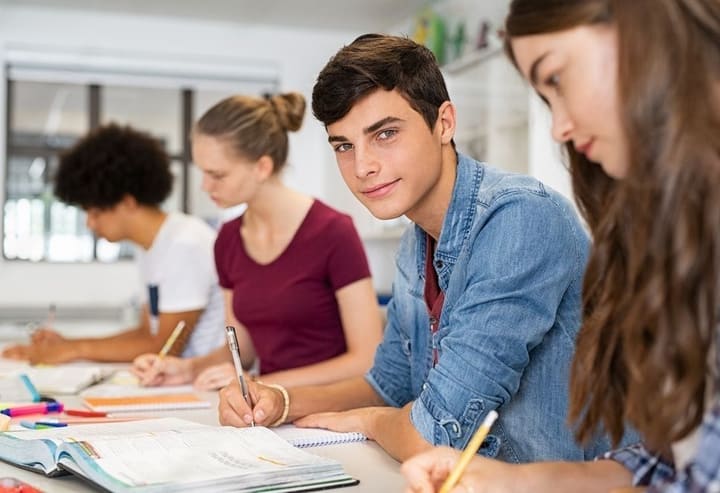 Groep oudere leerlingen die samen aan een lange tafel werkt