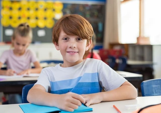 Leerling kijkt zelfverzekerd op van zijn werk